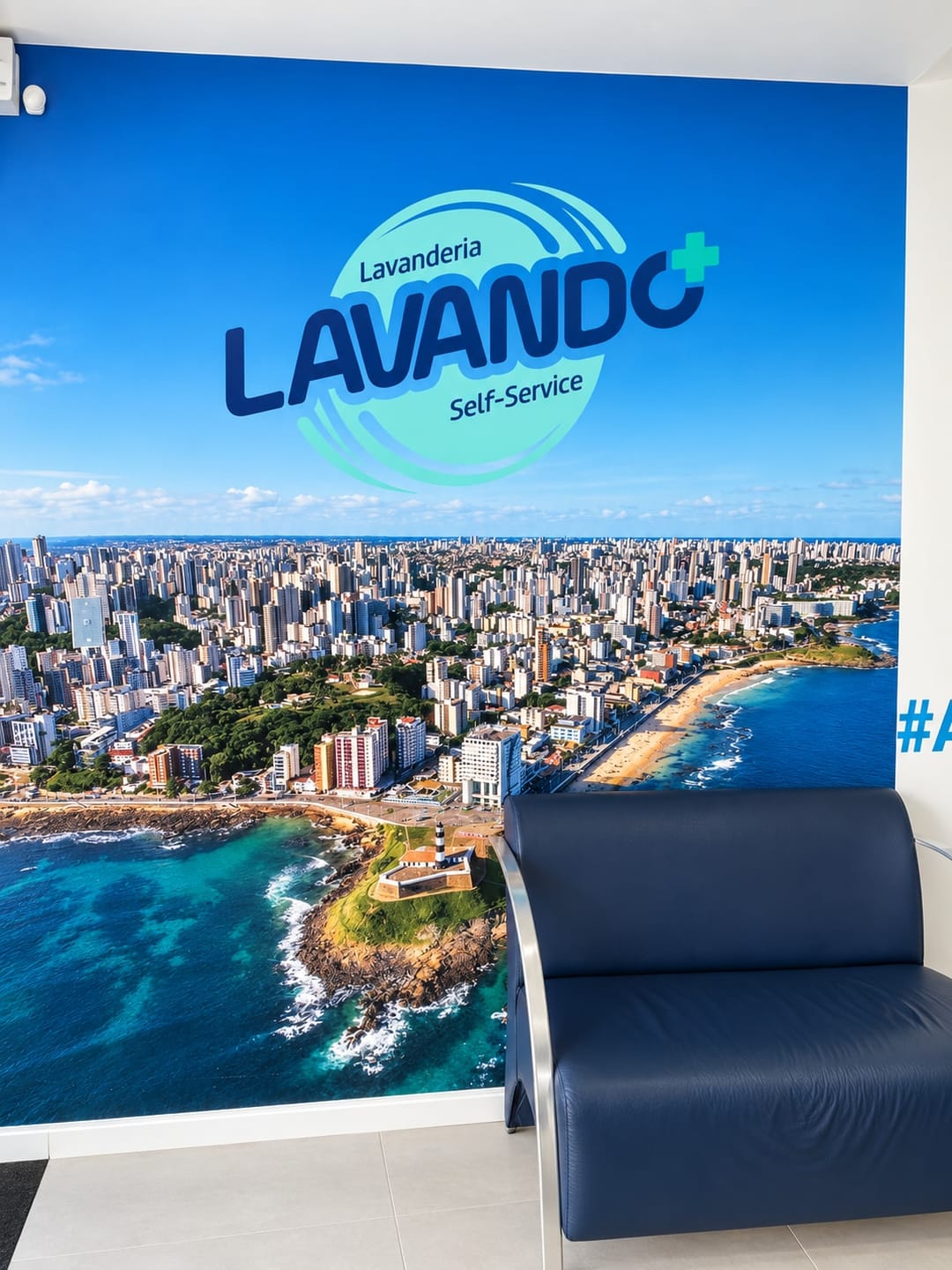 Mural with the Lavando Mais logo over an aerial view of Barra and its lighthouse, with a navy armchair in front