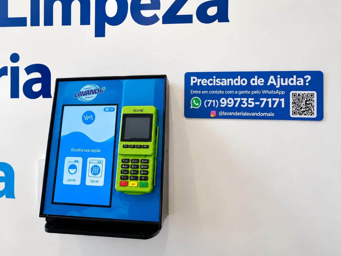 The payment kiosk on the wall, separate from the machines: the Escolha sua opção (choose your option) screen with the Lavar (wash) and Secar (dry) buttons, the card machine next to it and the help sign with the store WhatsApp